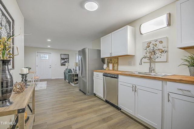 kitchen featuring butcher block countertops, white cabinets, sink, and appliances with stainless steel finishes