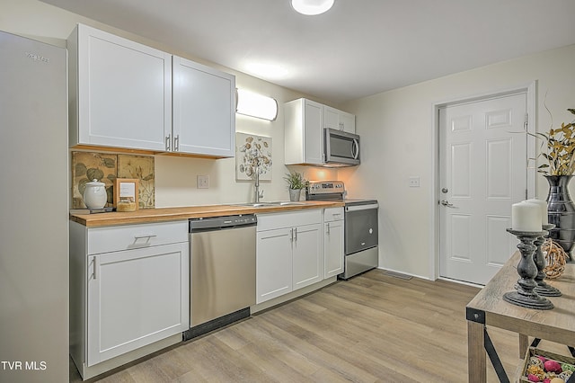 kitchen featuring white cabinetry, sink, stainless steel appliances, butcher block countertops, and light wood-type flooring