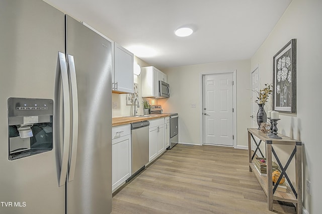 kitchen with white cabinets, sink, light hardwood / wood-style flooring, butcher block counters, and stainless steel appliances