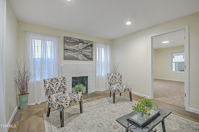 sitting room with hardwood / wood-style floors and a brick fireplace