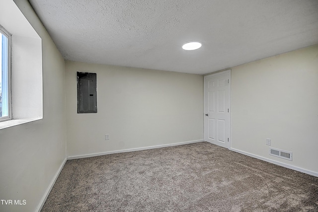 carpeted empty room with a textured ceiling and electric panel