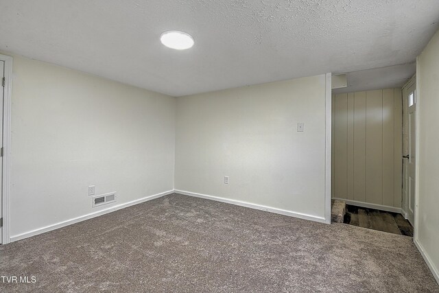 unfurnished room with dark colored carpet and a textured ceiling