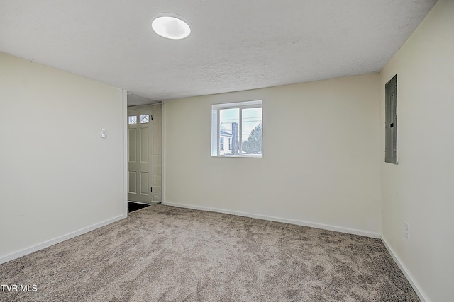 carpeted spare room with a textured ceiling and electric panel