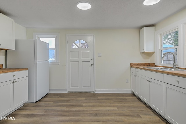 kitchen featuring white cabinets, a healthy amount of sunlight, butcher block counters, and sink