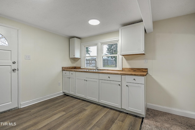 kitchen with wood counters, sink, a textured ceiling, dark hardwood / wood-style flooring, and white cabinetry