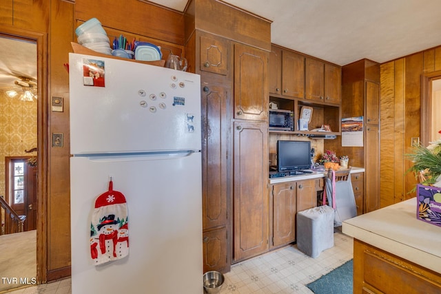 kitchen featuring wooden walls and white fridge