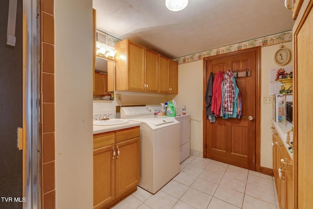 laundry room featuring washer and clothes dryer, sink, light tile patterned floors, and a textured ceiling