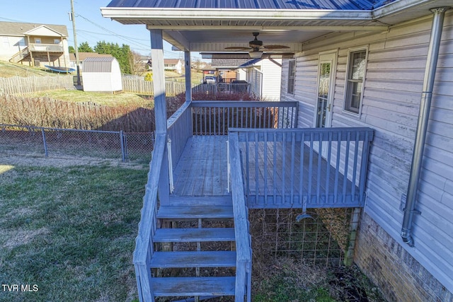 deck with a yard, ceiling fan, and a storage shed