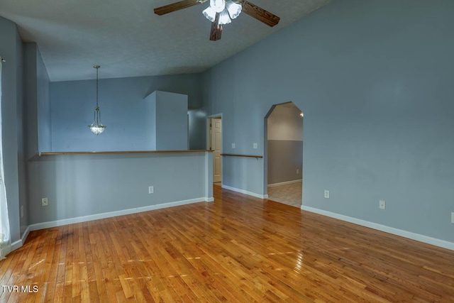 unfurnished living room featuring ceiling fan, light hardwood / wood-style flooring, high vaulted ceiling, and a textured ceiling