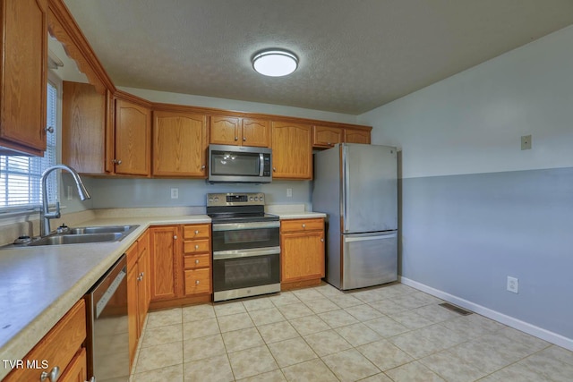 kitchen featuring light tile patterned flooring, appliances with stainless steel finishes, a textured ceiling, and sink