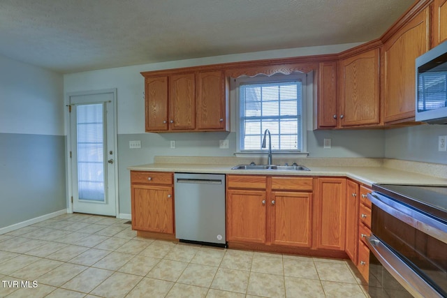 kitchen with light tile patterned floors, a textured ceiling, stainless steel appliances, and sink