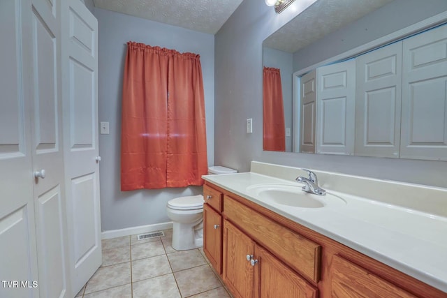 bathroom with tile patterned flooring, vanity, toilet, and a textured ceiling