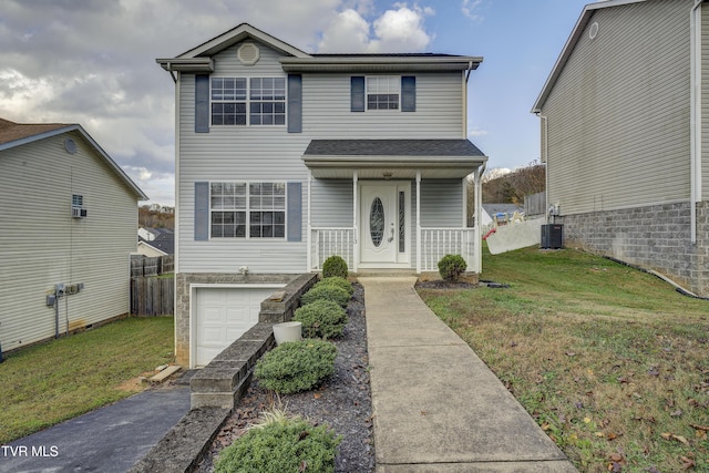 view of property featuring cooling unit, a front lawn, and a garage