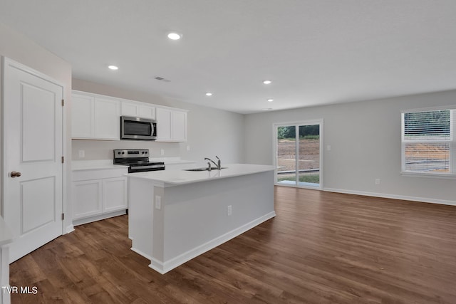 kitchen with white cabinetry, sink, stainless steel appliances, dark hardwood / wood-style floors, and an island with sink