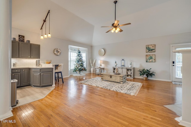 unfurnished living room featuring ceiling fan, high vaulted ceiling, and light wood-type flooring