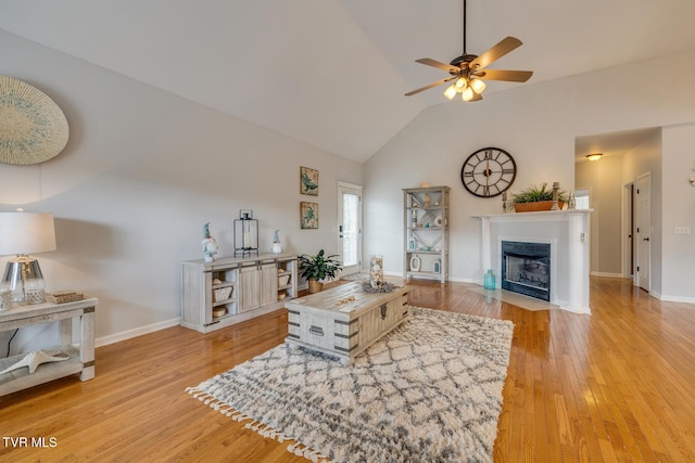 living room with ceiling fan, light hardwood / wood-style flooring, and vaulted ceiling