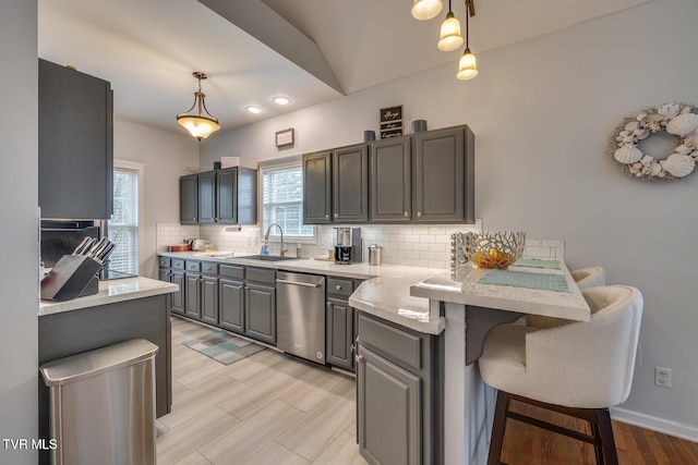 kitchen featuring gray cabinetry, dishwasher, sink, kitchen peninsula, and pendant lighting