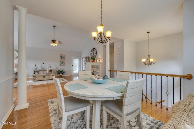 dining space with ceiling fan with notable chandelier, lofted ceiling, light hardwood / wood-style flooring, and decorative columns