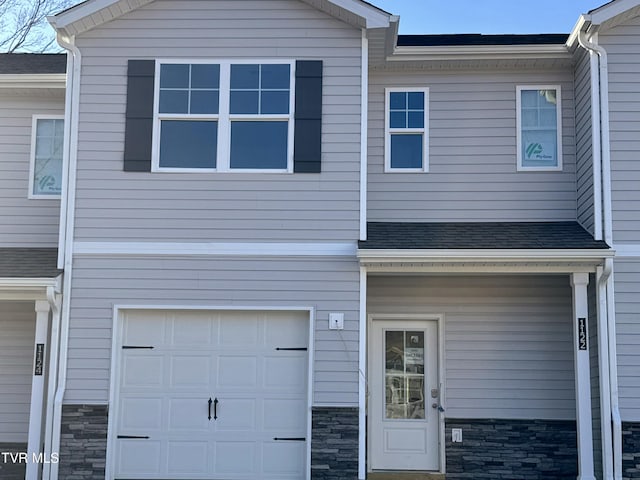 townhome / multi-family property with stone siding and an attached garage