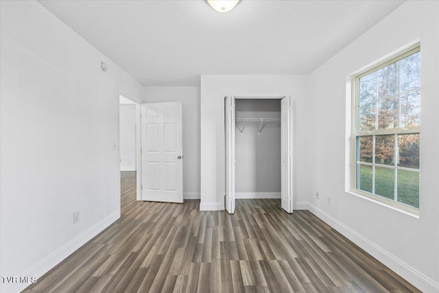 unfurnished bedroom with multiple windows, a closet, and dark hardwood / wood-style flooring