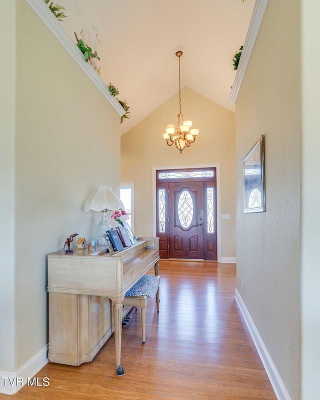 foyer featuring light wood-style floors, a chandelier, high vaulted ceiling, and baseboards