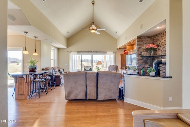 living area featuring light wood-style flooring, high vaulted ceiling, and a ceiling fan