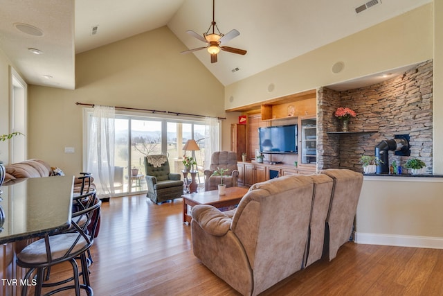 living room with high vaulted ceiling, wood finished floors, visible vents, and baseboards