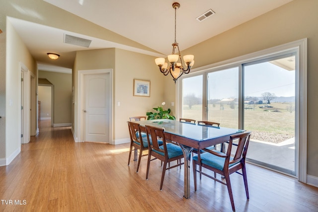 dining room with lofted ceiling, a chandelier, visible vents, and light wood-style floors