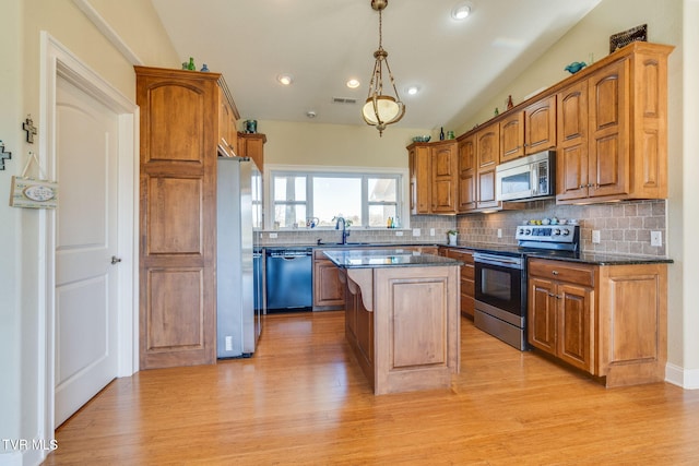 kitchen with stainless steel appliances, tasteful backsplash, a sink, and a kitchen island