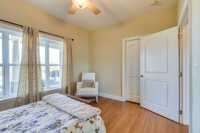 bedroom with a ceiling fan, baseboards, and light wood finished floors