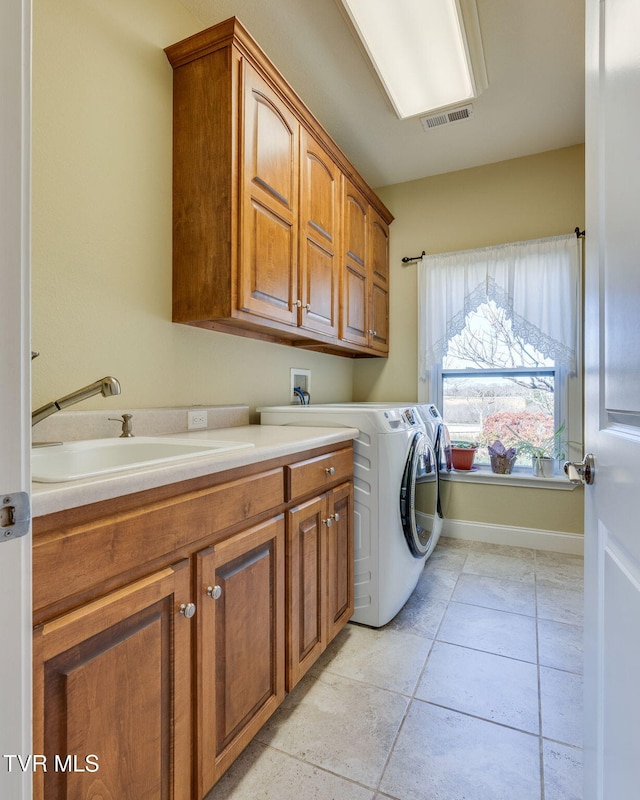 laundry area featuring cabinet space, baseboards, visible vents, separate washer and dryer, and a sink