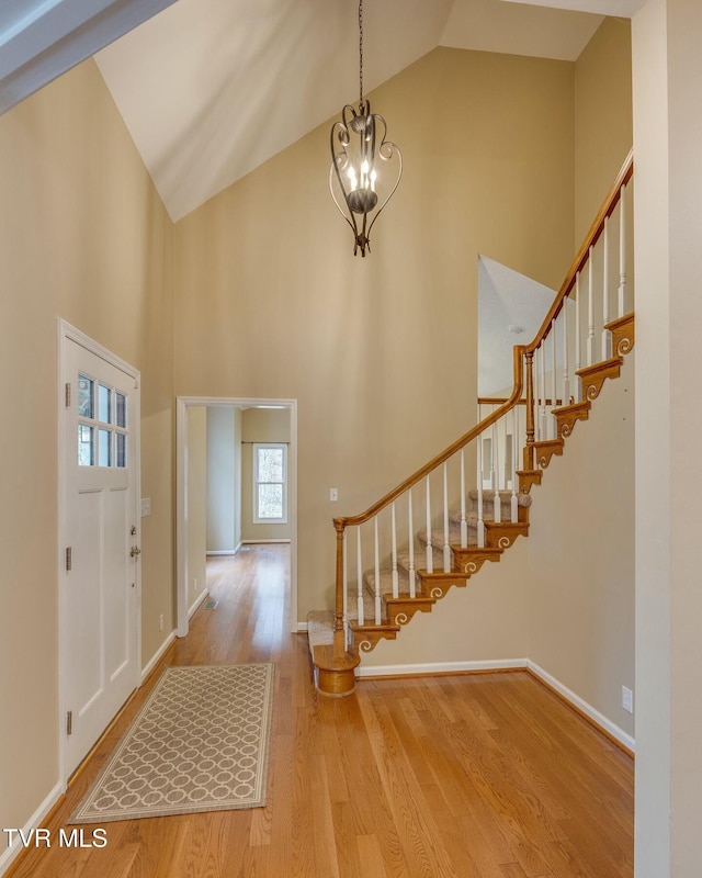 entrance foyer with high vaulted ceiling, a notable chandelier, and light wood-type flooring