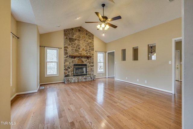 unfurnished living room with a stone fireplace, ceiling fan, light hardwood / wood-style flooring, and lofted ceiling