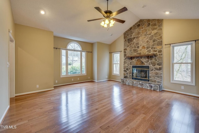 unfurnished living room featuring a stone fireplace, ceiling fan, light hardwood / wood-style floors, and lofted ceiling