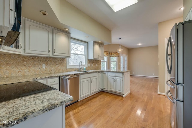 kitchen featuring white cabinetry, sink, hanging light fixtures, kitchen peninsula, and appliances with stainless steel finishes