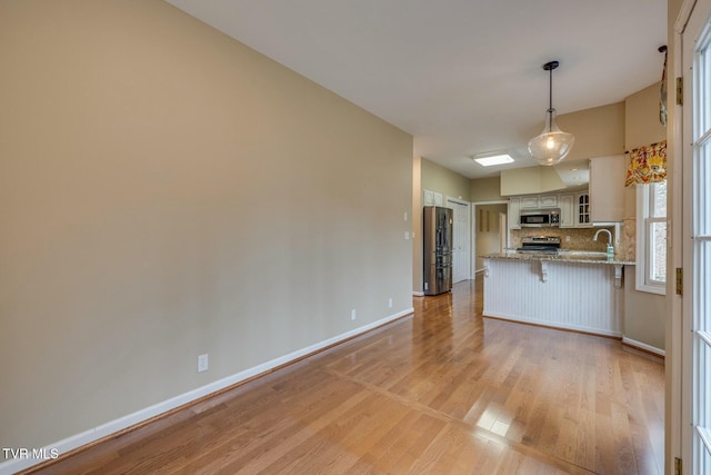 kitchen with white cabinetry, stainless steel appliances, tasteful backsplash, kitchen peninsula, and a breakfast bar