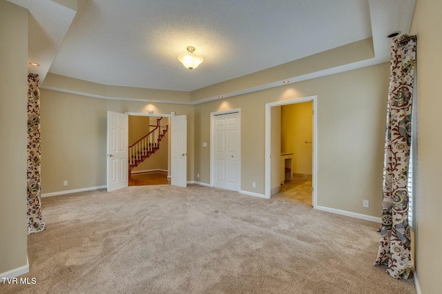 unfurnished bedroom featuring light colored carpet, a textured ceiling, connected bathroom, and a closet