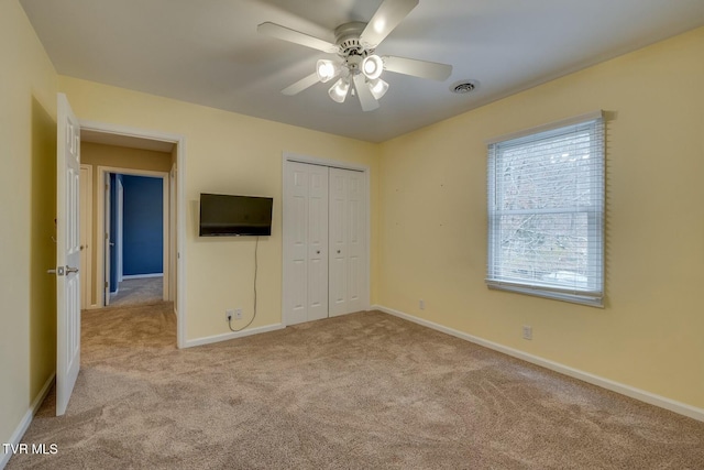 unfurnished bedroom with ceiling fan, light carpet, and a closet