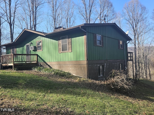 view of side of property with a lawn, cooling unit, and a deck