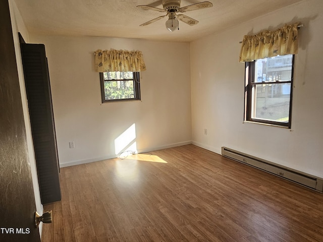 empty room featuring hardwood / wood-style floors, ceiling fan, and a baseboard heating unit