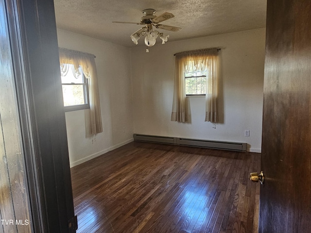 unfurnished room featuring ceiling fan, a healthy amount of sunlight, baseboard heating, and dark wood-type flooring