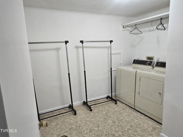 washroom featuring a textured ceiling, washing machine and dryer, and ornamental molding