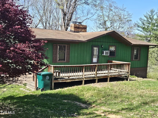 view of front facade with a deck, a chimney, and a front lawn