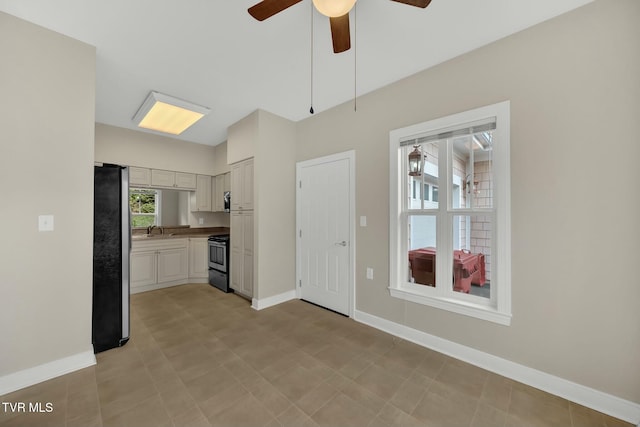 kitchen featuring sink, ceiling fan, black range with electric cooktop, white cabinetry, and stainless steel refrigerator