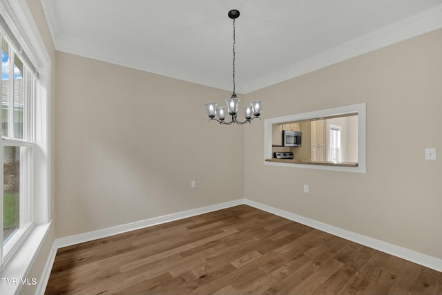 empty room with wood-type flooring, ornamental molding, and an inviting chandelier