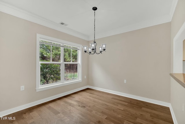 unfurnished dining area featuring wood-type flooring, ornamental molding, and a chandelier