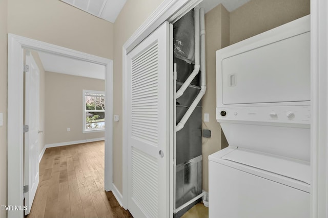 clothes washing area featuring wood-type flooring and stacked washer and dryer