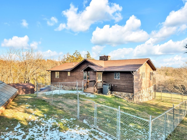 back of property with central AC unit and a lawn