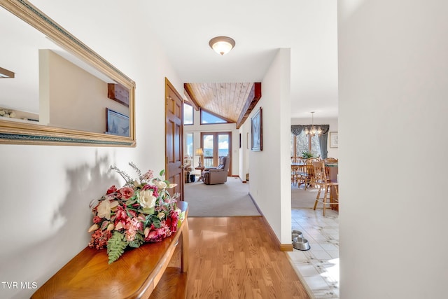 hall featuring hardwood / wood-style flooring, vaulted ceiling, and a notable chandelier