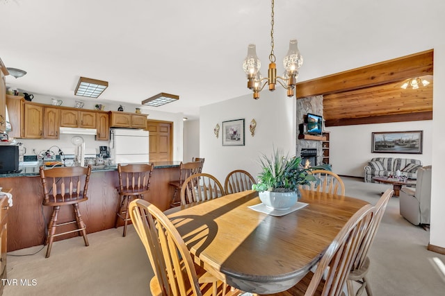 dining space with an inviting chandelier, a fireplace, beam ceiling, and light carpet